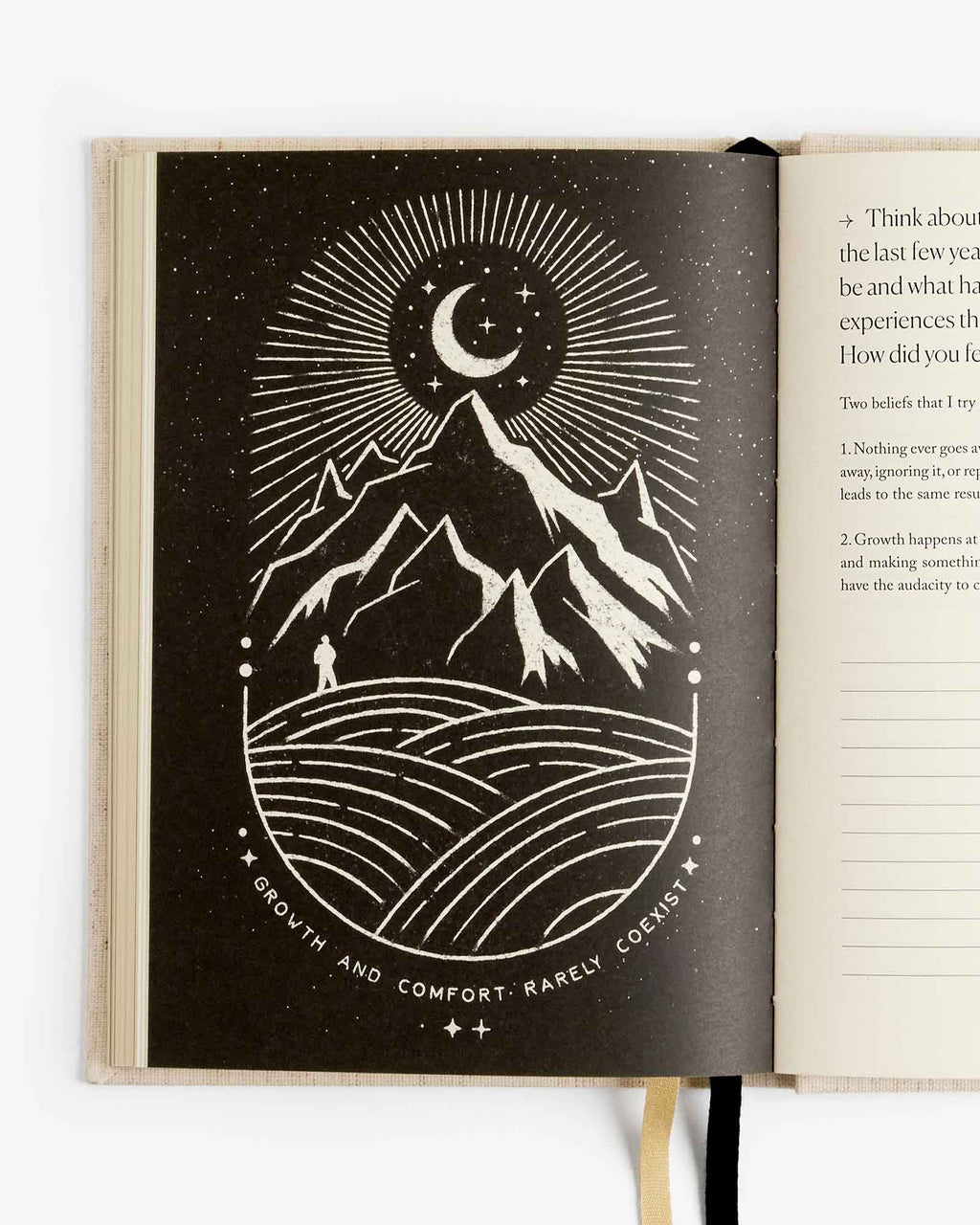 Open journal spread with dark night theme cover art and moon-mountain line drawing