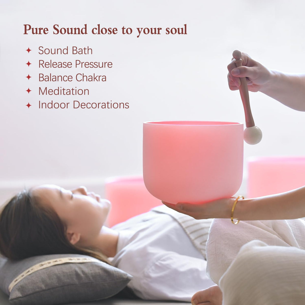 Pink frosted crystal singing bowl held above a sound bath setup with mallet