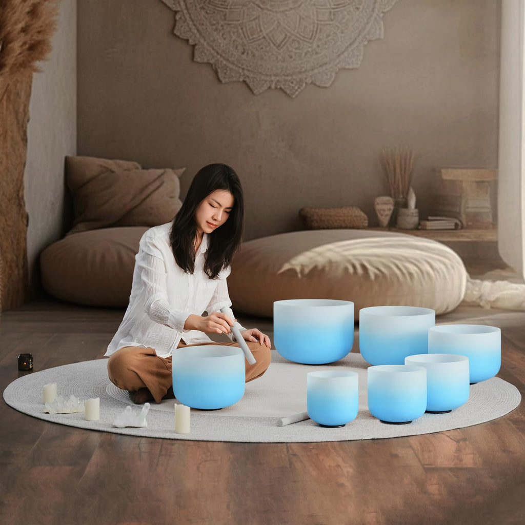 Blue frosted crystal singing bowls set with mallets, arranged on a meditation mat