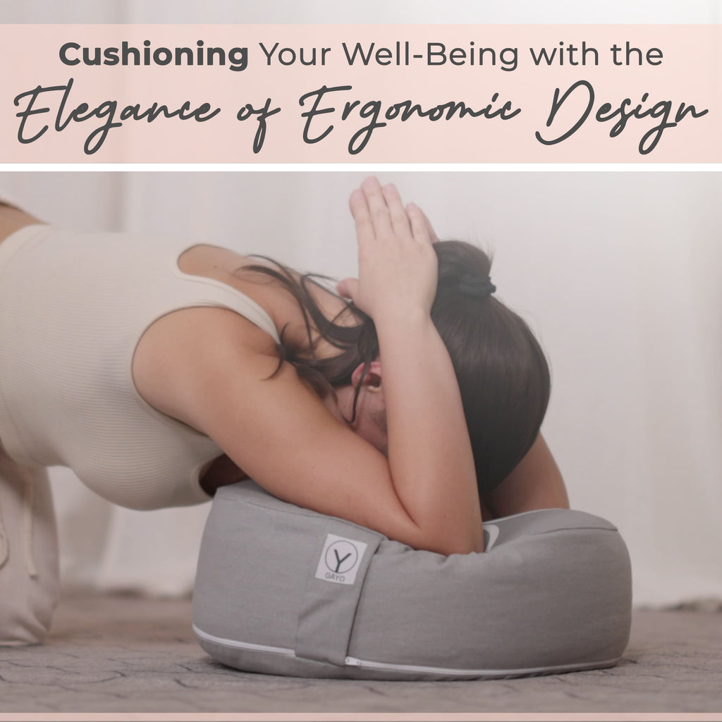Gray round meditation cushion with logo patch, held in an ergonomic sitting position.