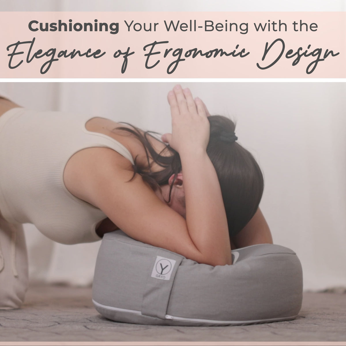 Gray round meditation cushion with logo patch, held in an ergonomic sitting position.