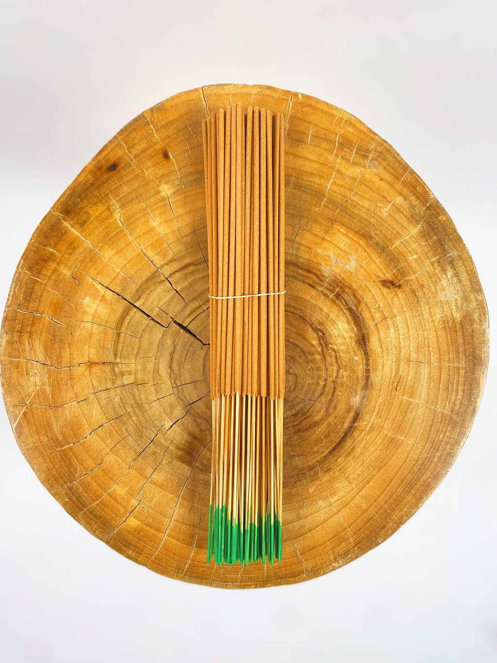 Incense sticks bundle with green-tipped ends, bound with a tan paper band