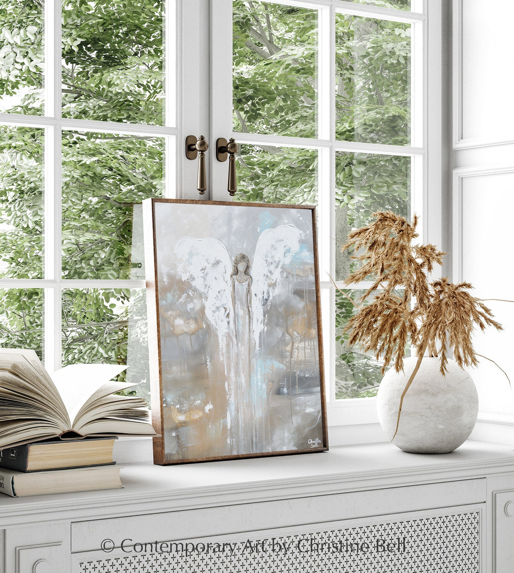 Framed angel guardian print on display, featuring pale blue and gold abstract scene